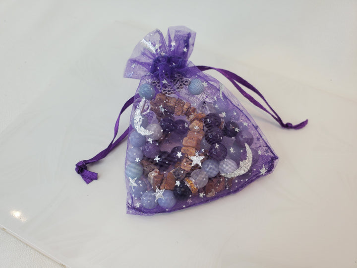 A clsoe purple organza bag, featuring a printed celestial design with bracelets inside.