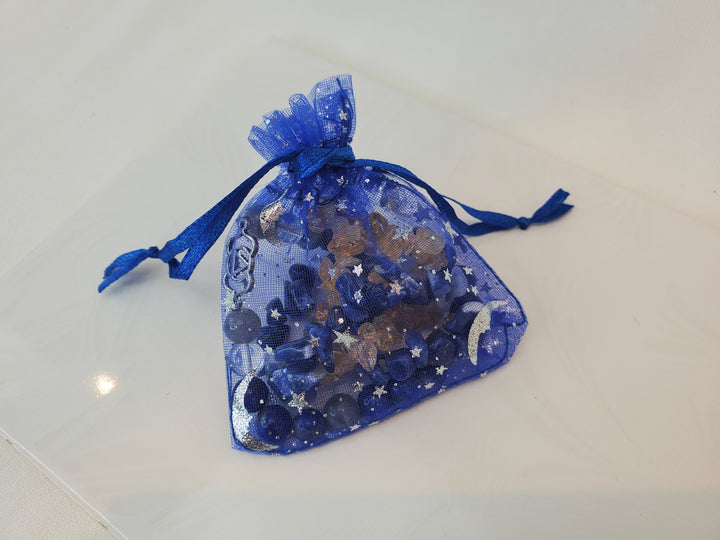 A blue organza bag, featuring a printed celestial design with bracelets inside.