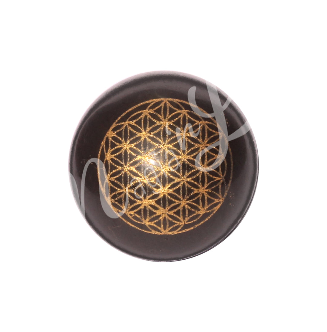 A sphere made of black tourmaline with a flower of life symbol engraved and painted gold.