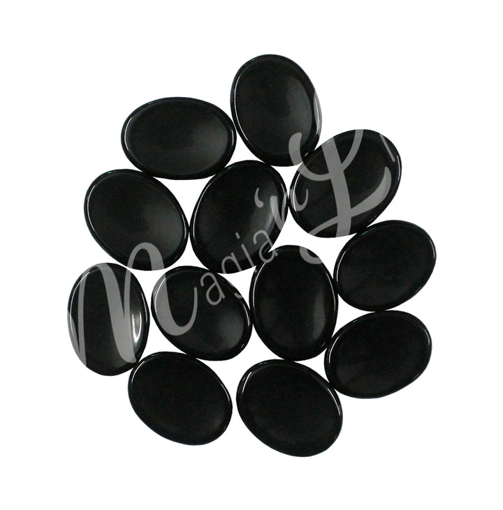 A collection of polished black stones with smooth, oval shapes, showing natural color variations and patterns.
