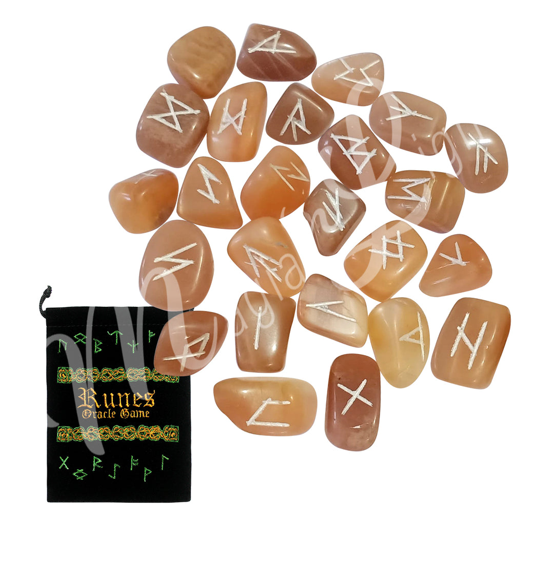 A set of peach moonstone runestones with engraved and painted silver symbols, displayed with a black velvet pouch. The pouch is embroidered with the words "runes oracle game", as well as runic symbols.