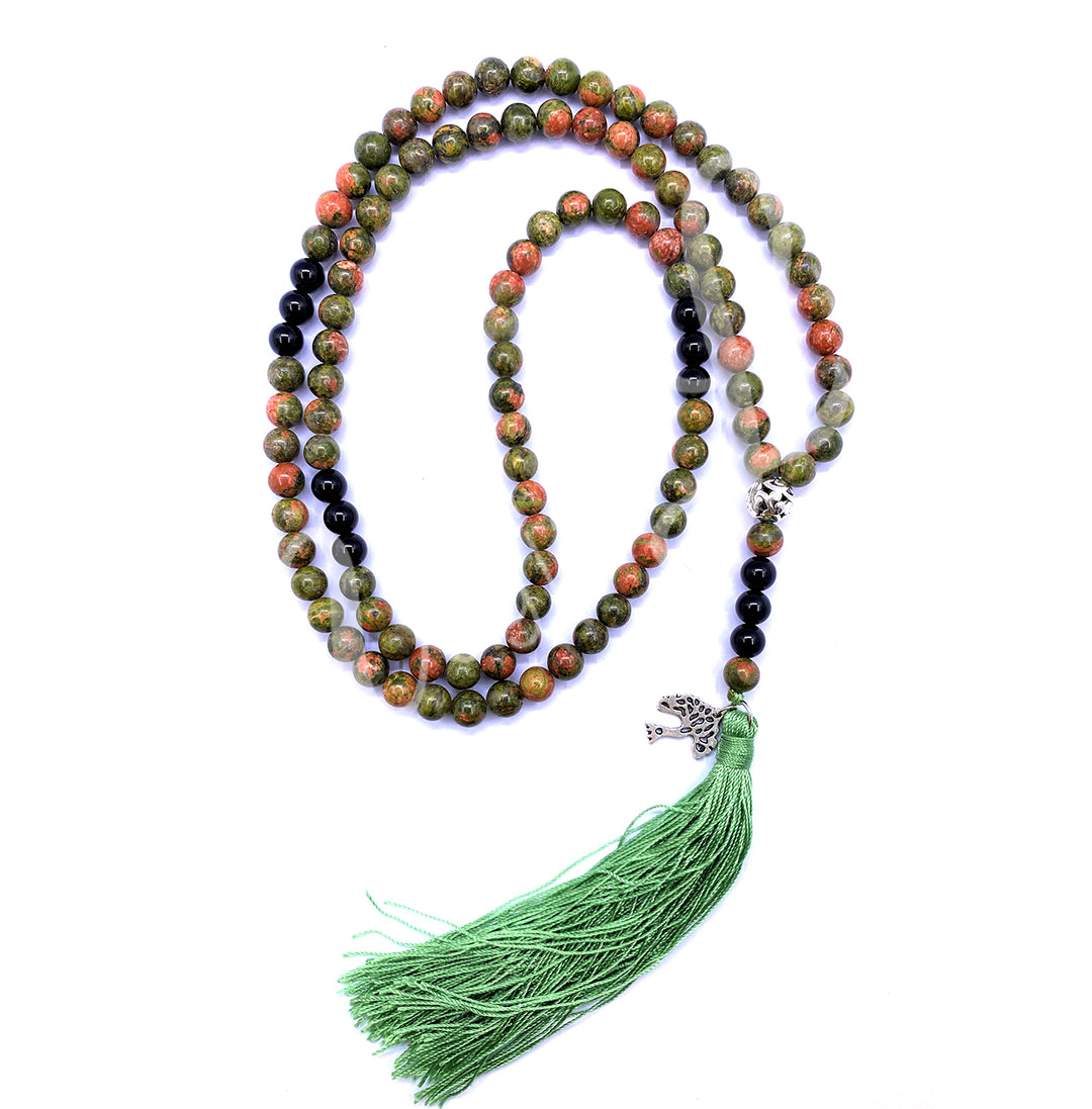 An unakite and black onyx mala necklace with polished round beads with a tree of life charm and a long green tassel.