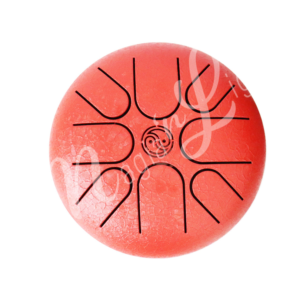 A top view of a red iron tongue drum with a speckled finish, featuring multiple U-shaped cutout tongues and a yin yang symbol in the center.