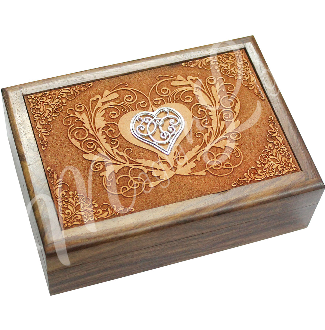 A wooden box features a heart design on the lid, with a metal heart charm affixed on top.
