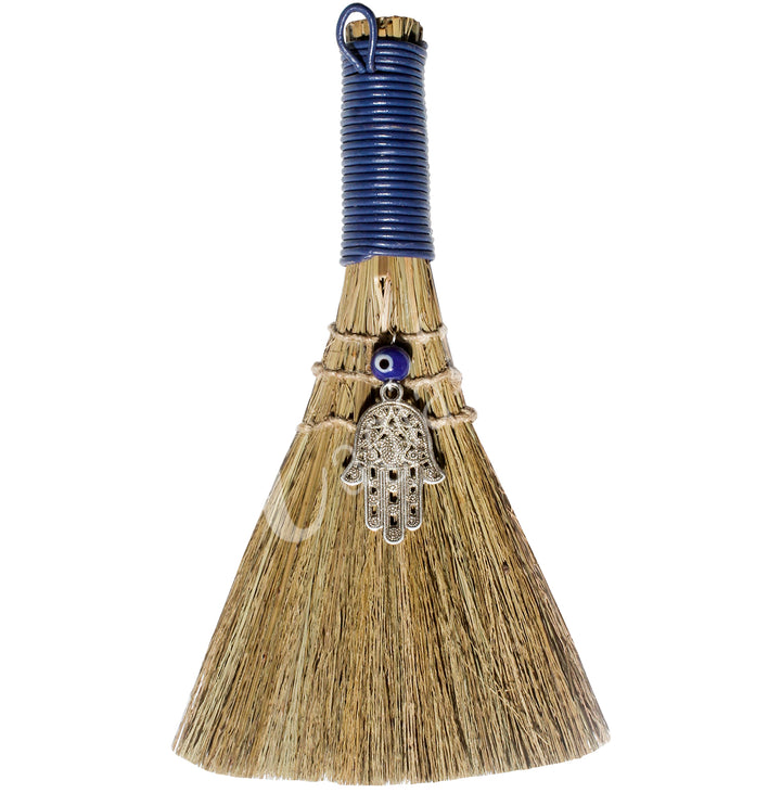 A witch's broom with a blue leather cord on top, featuring a straw base, an evil eye beads and Hand of Fatima.