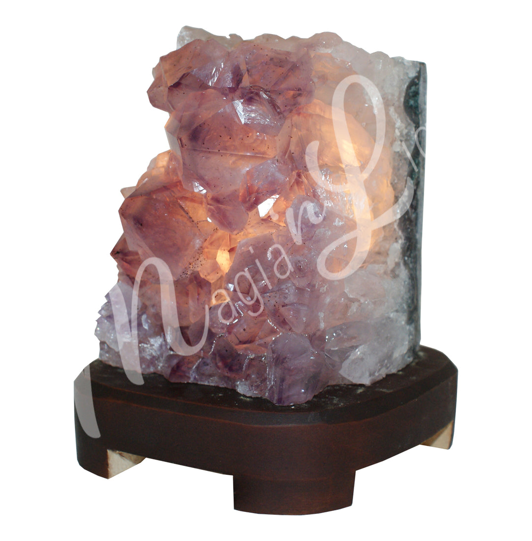 One side polished druse amethyst lamp on a dark wooden base with the light on.