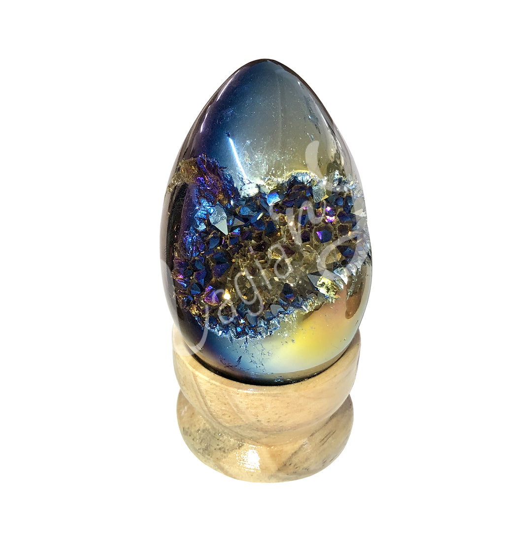 Egg-shaped crystal with a vivid metallic blue and gold surface, featuring a central band of sparkling druzy crystals, displayed on a light wooden stand.