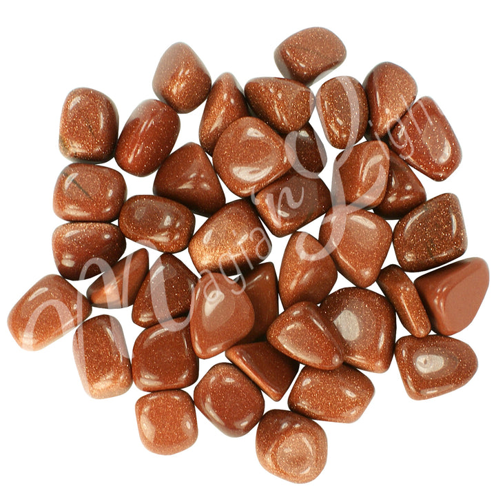 Collection of polished tumbled stones in shades of orange with little golden stitch, arranged together in a circular pile.