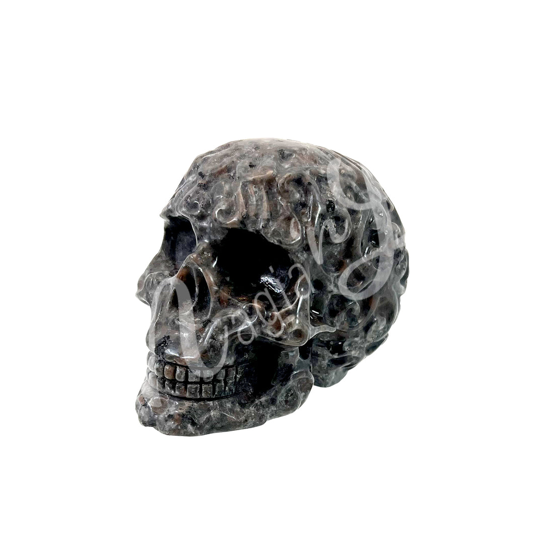 Polished gemstone skull carving with detailed features in dark gray and smoky tones.