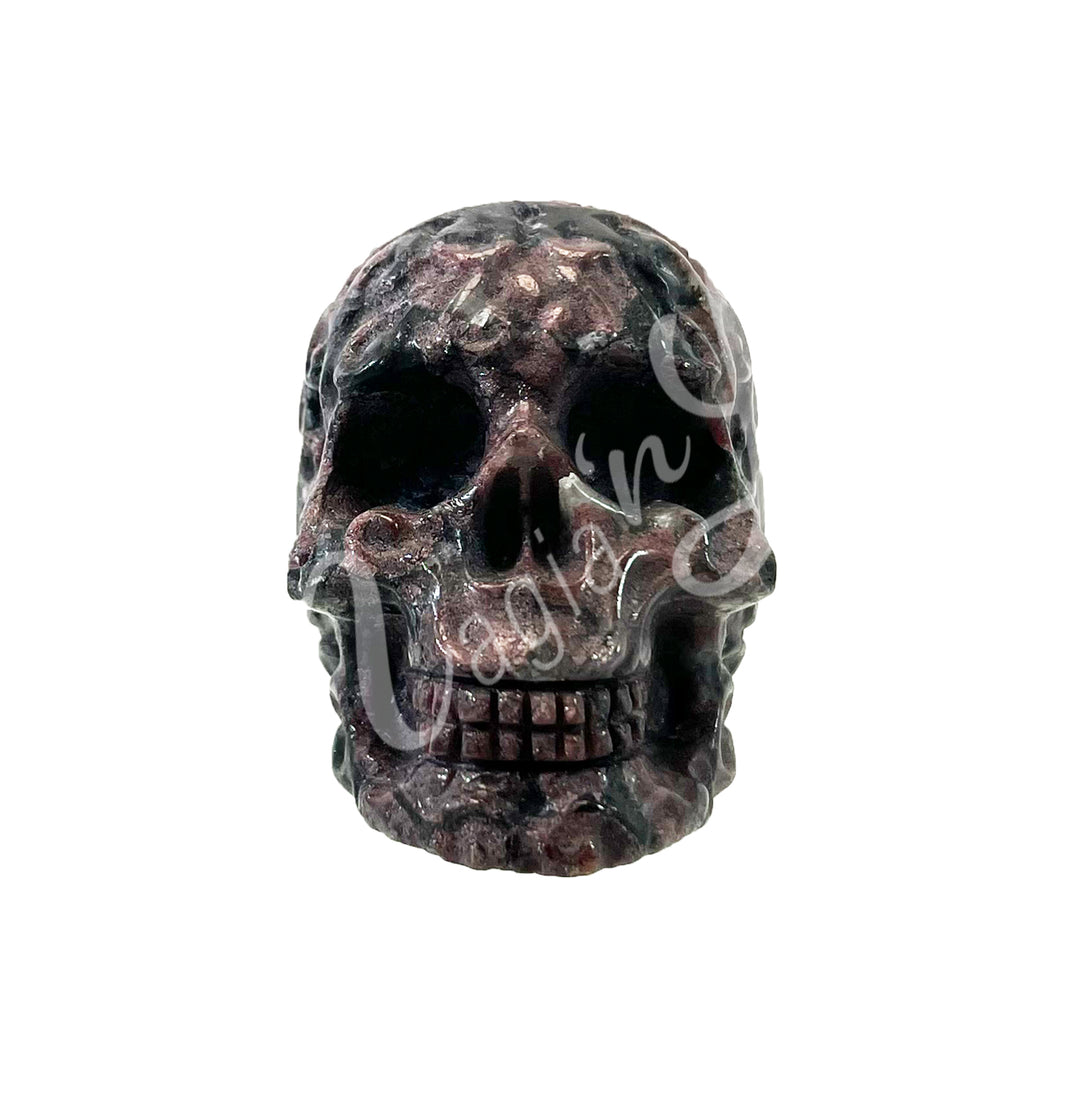 Polished gemstone skull carving with detailed features in black and purple tones.