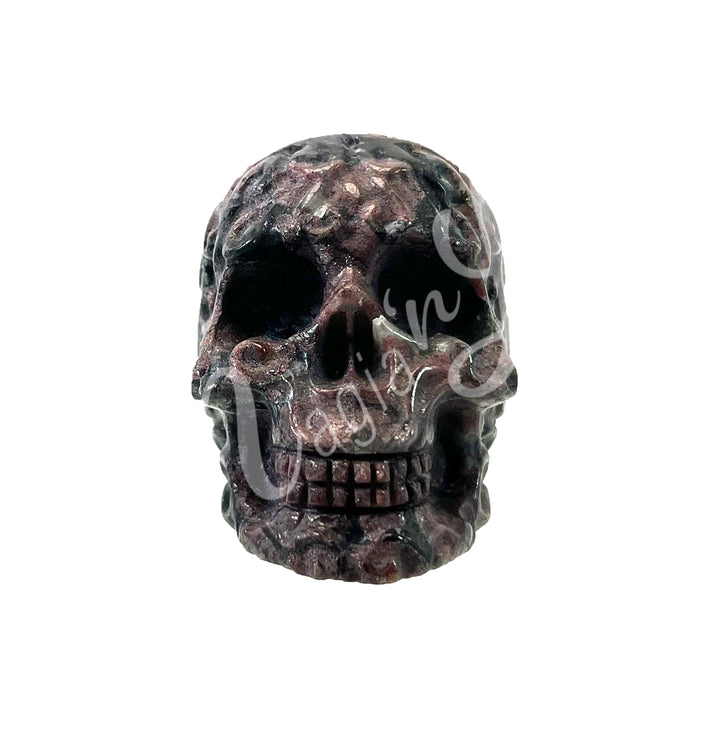 Polished gemstone skull carving with detailed features in black and purple tones.