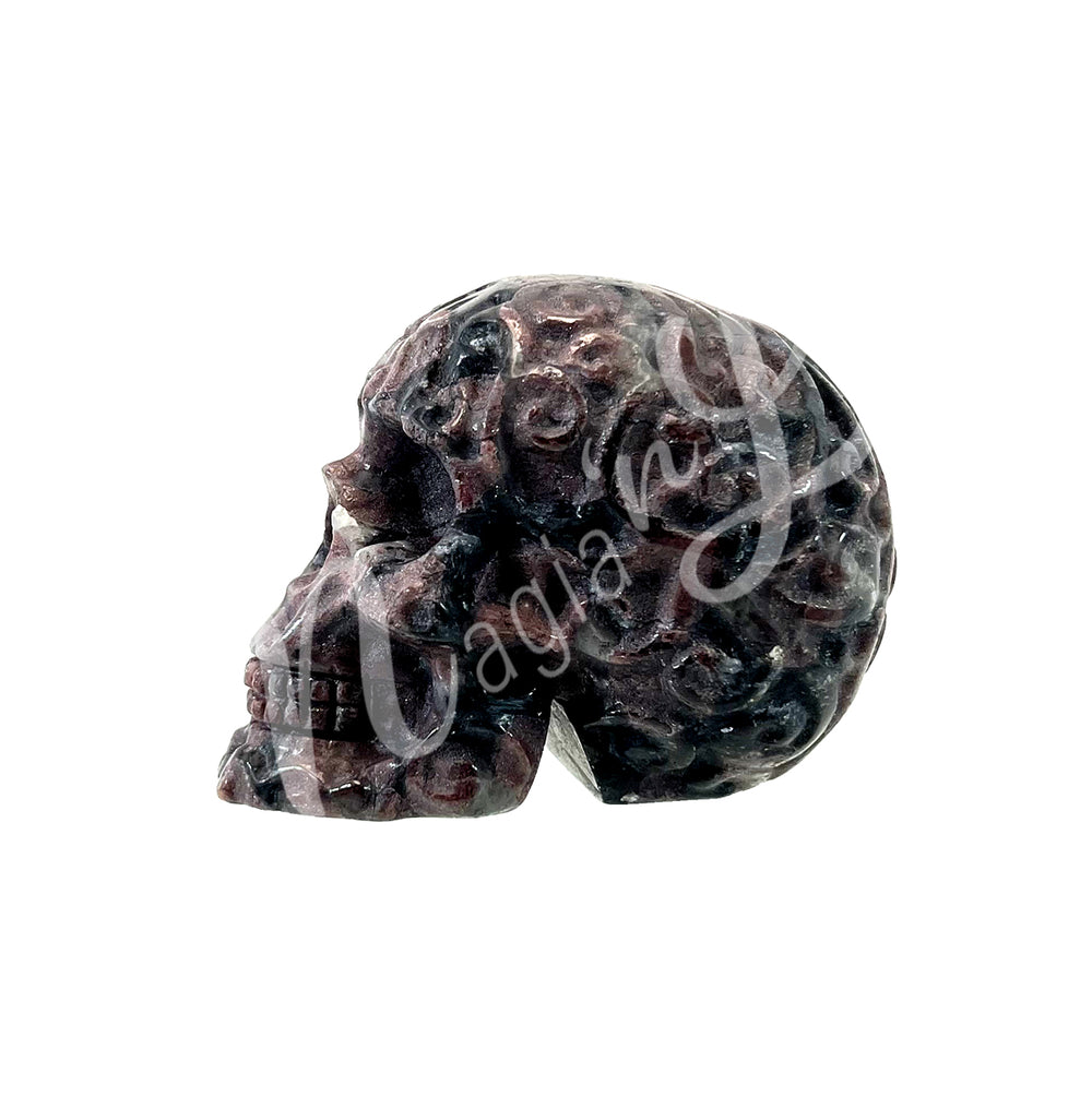 Polished gemstone skull carving with detailed features in black and purple tones. Seen from the side.