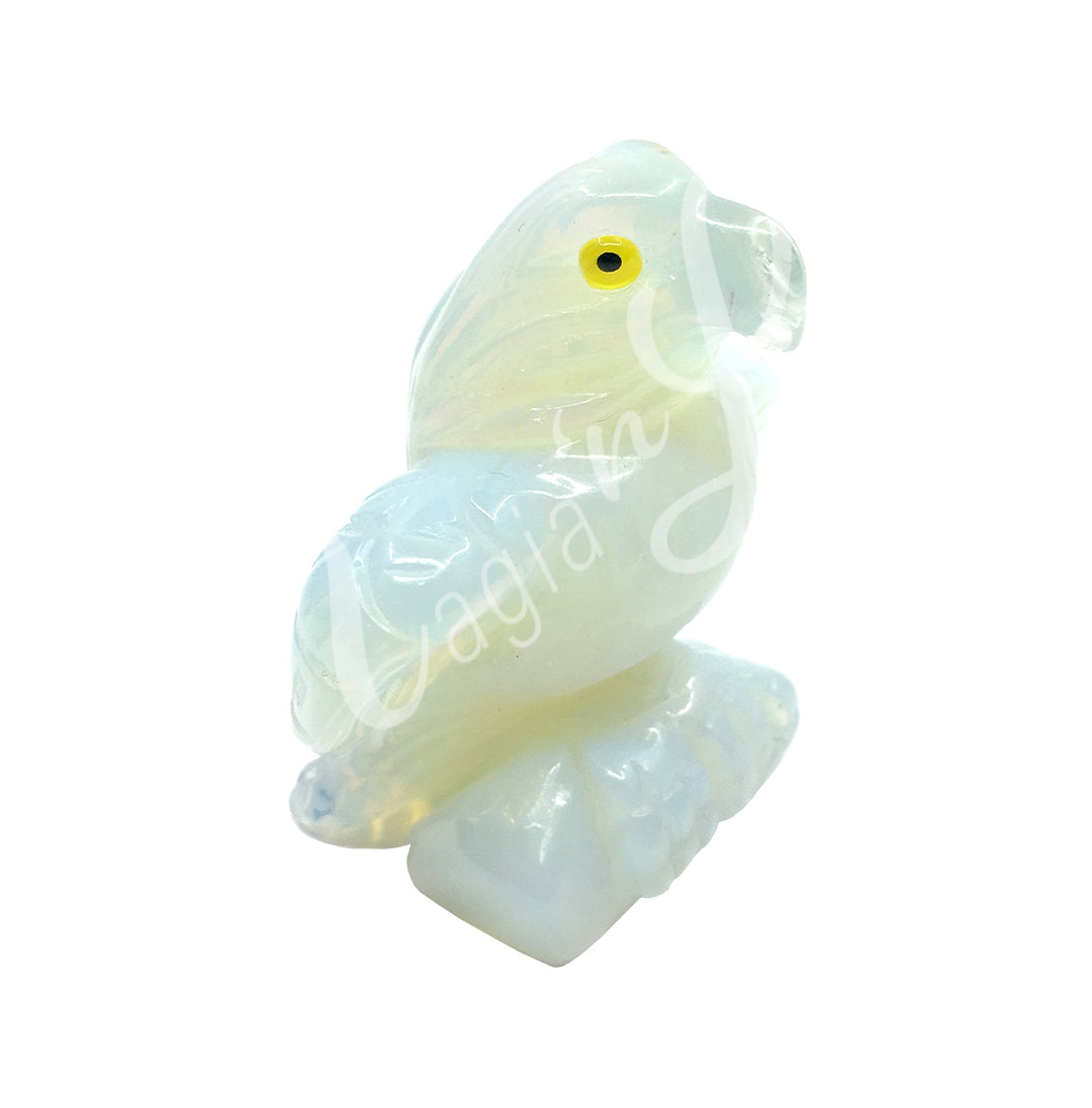 A carving of a bird with a yellow eye made of Opalite.