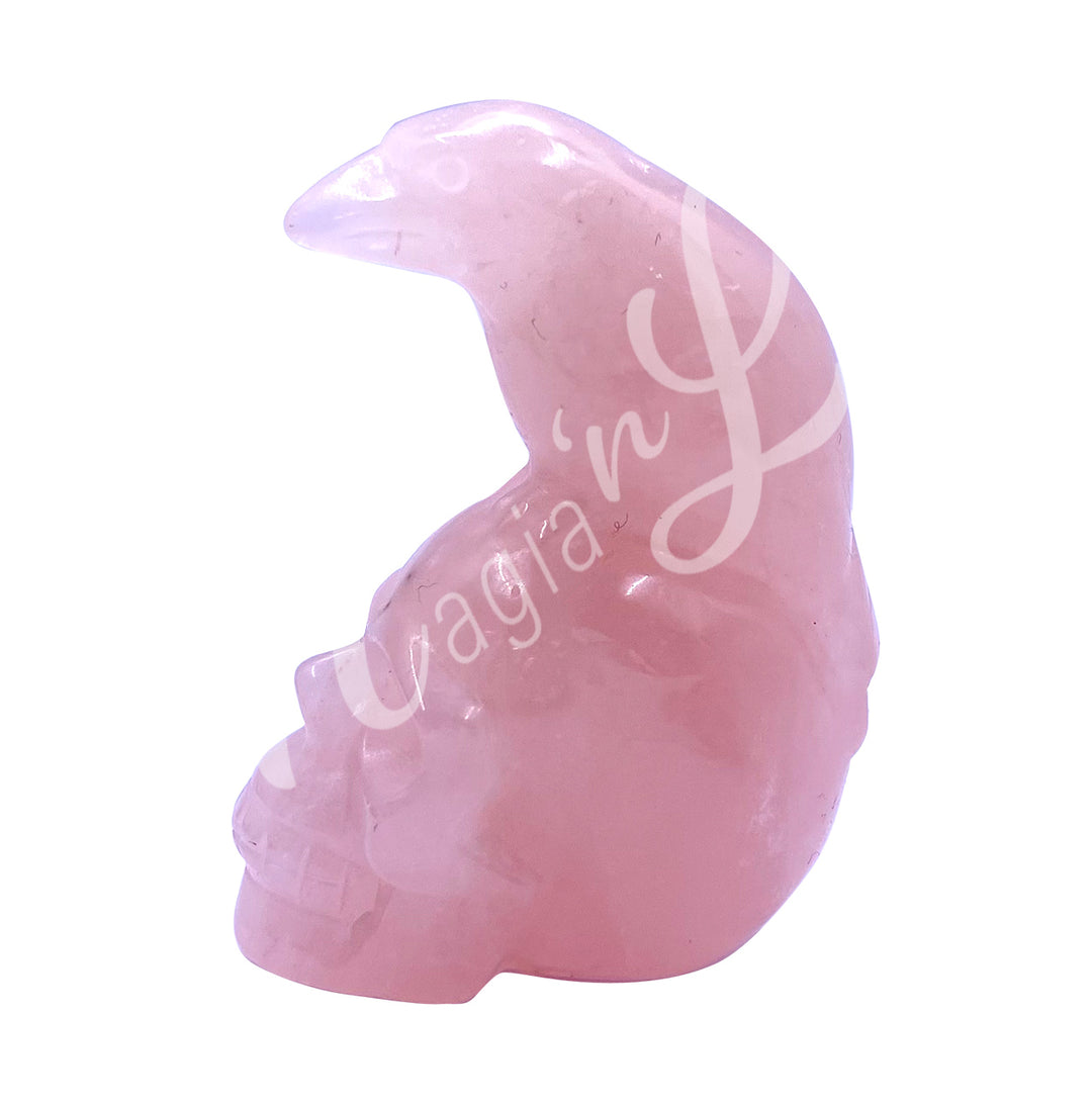 A polished raven on a skull carving made of rose quartz.