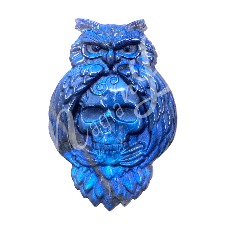 A carving of an owl with a skull to replace the belly, made of labradorite, seen with a different color shade.