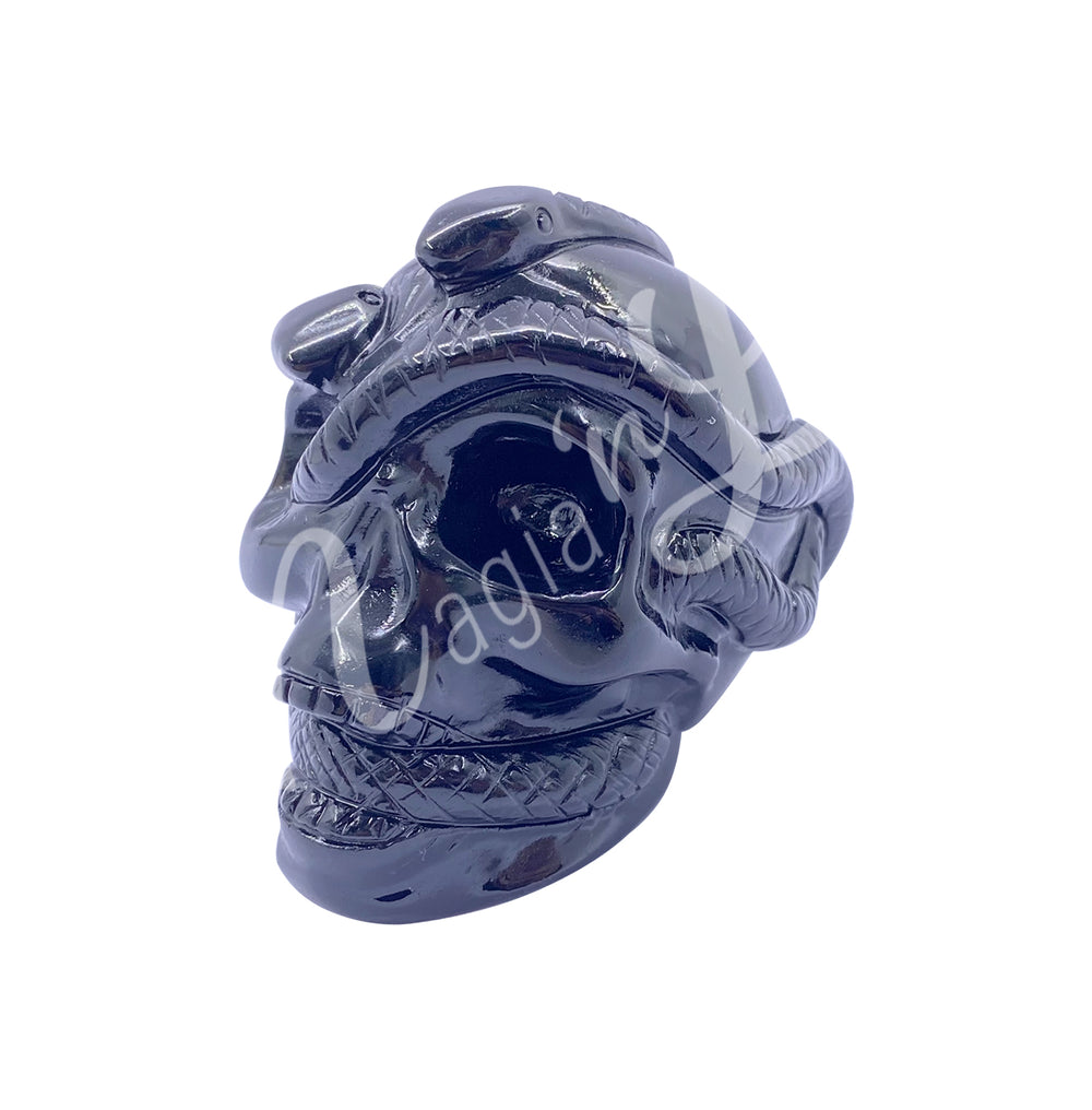 Polished gemstone skull with a snake carving made of black obsidian. Seen with an angle.