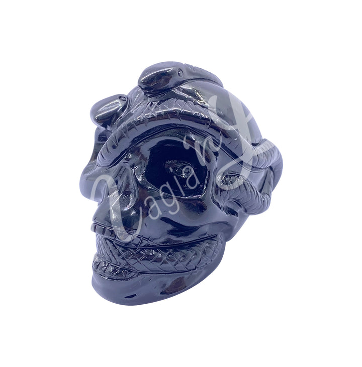 Polished gemstone skull with a snake carving made of black obsidian. Seen with an angle.