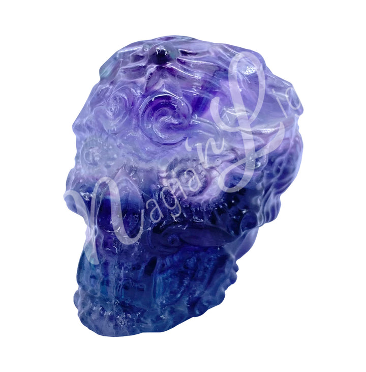 Polished gemstone skull with a design carving made of fluorite, seen with a different color shade.