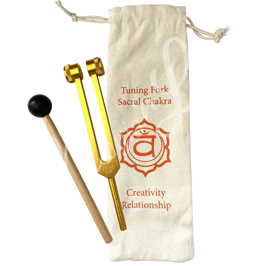 A Sacral Chakra tuning fork set. The set includes:
Orange tuning fork labeled "Sacral Chakra."
Wooden mallet with a black rubber head for striking the tuning fork.
Drawstring pouch with the following printed on it:
"Tuning Fork Sacral Chakra"
A symbol representing the Sacral Chakra.
Words "Creativity" and "Relationship."