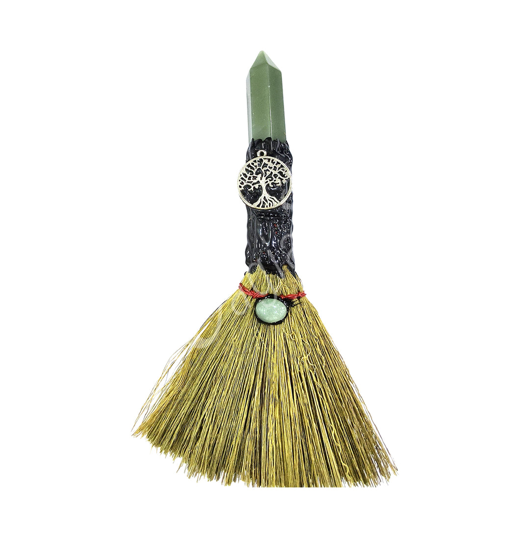 A decorative witch's broom with a tree of life charm attached to the handle, made from a green aventurine point and a bundle of straws for the broom.