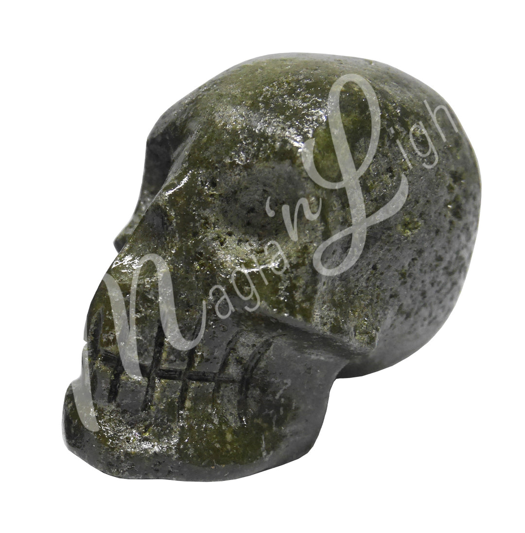 A polished skull carving made of epidote, features natural holes in the skull.