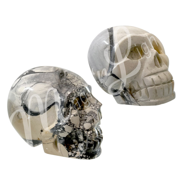 Two polished skull carvings made of Maligano jasper, shown in two different color shades.