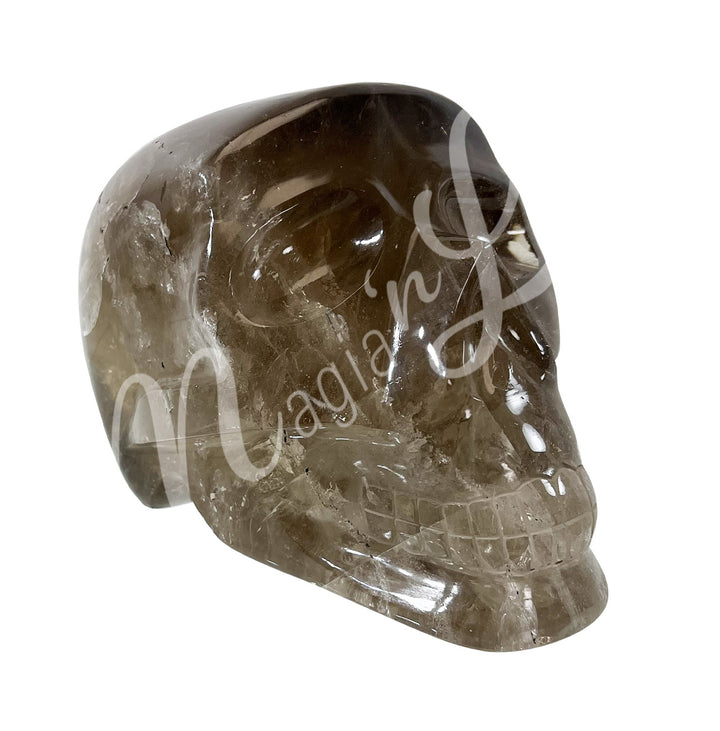 Polished gemstone skull carving made of smoky quartz. Seen with an angle.
