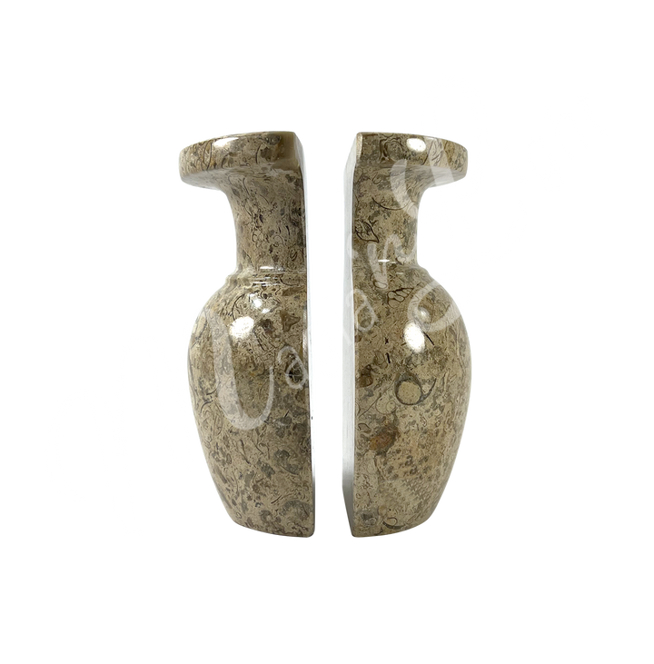 Two polished halves of a coral stone vase, positioned side by side to show the split down the middle, with a rounded body, narrow neck, and flared rim.