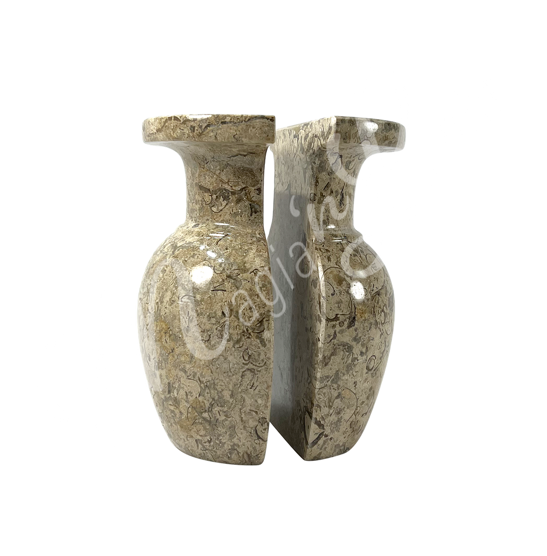 Two polished halves of a coral stone vase, positioned side by side to show the split down the middle, with a rounded body, narrow neck, and flared rim.