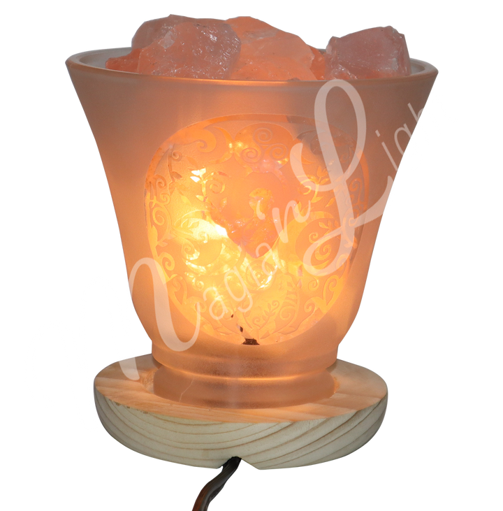Lit decorative frosted glass lamp with etched Goddess design, wooden base, and rose quartz crystals glowing warmly.