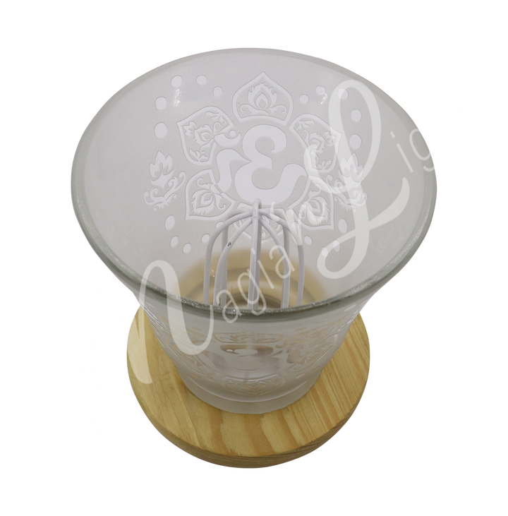 Empty decorative frosted glass cup lamp with etched Om in a lotus flower design, wooden base, metal piece in the middle.