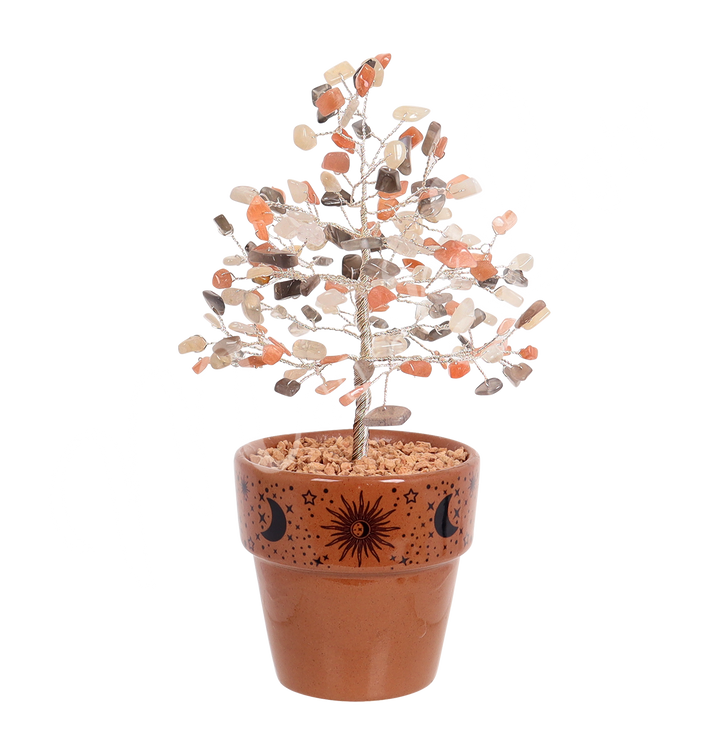 A gemstone bonsai tree with branches made of wire and decorated with multi moonstone chips, set in a terracotta pot decorated with moon, stars and sun designs.