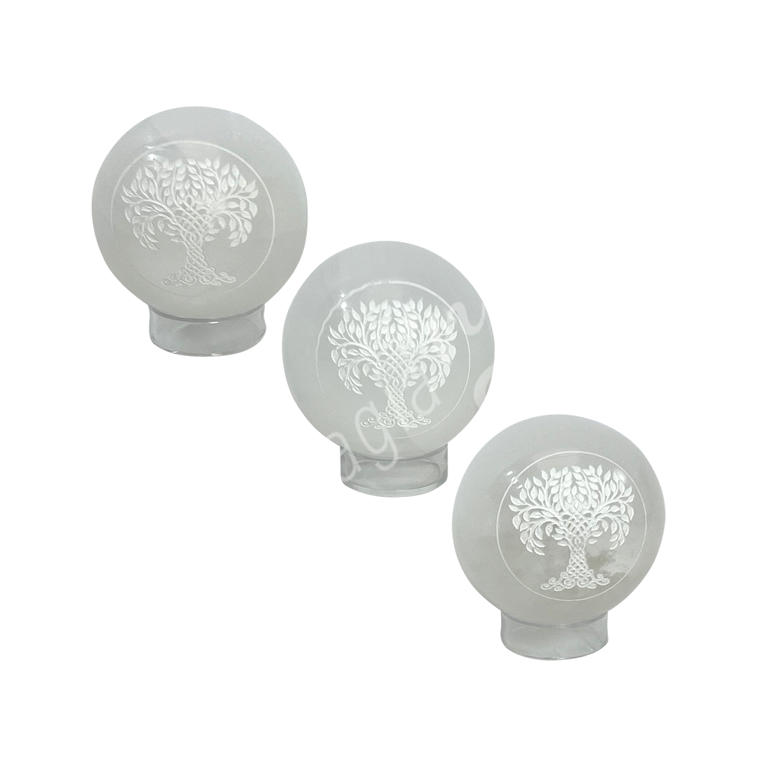 Three clear glass sphere with a tree of life symbol engraved and painted white on stand.