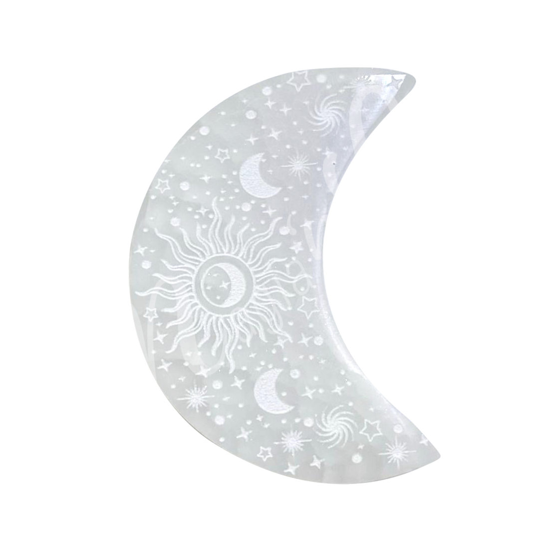 A moon-shaped Selenite crystal engraved with stars, crescent moons, a central sun, and spiral galaxy designs.