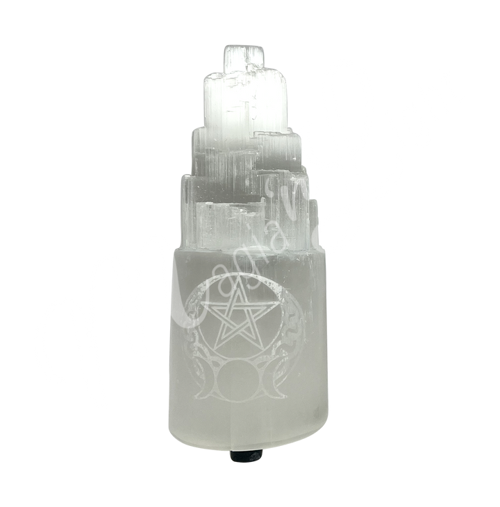 Selenite iceberg carving with black rubber feet. The lamp is engraved with a white triple moon and a pentacle, seen with an other angle.
