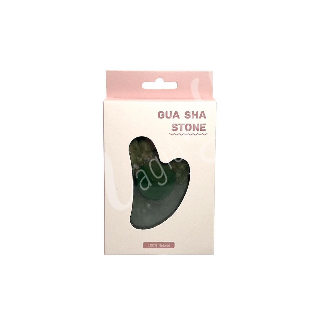 Jade gua sha stone in retail packaging labeled “Gua Sha Stone,” with a heart-shaped cutout revealing the product inside and “100% Natural” printed at the bottom.