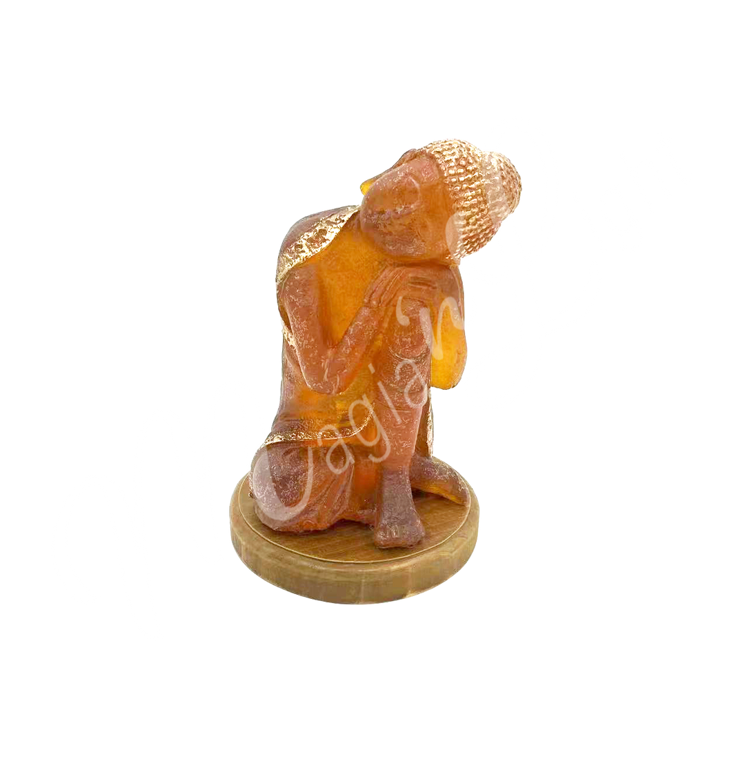 A resin lamp and statue representing the deity Buddha, set on a round wooden base.