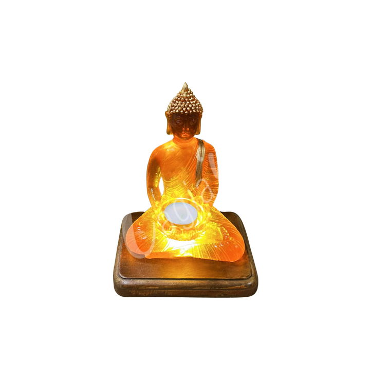 A resin lamp and statue representing the deity Buddha, holding a lotus flower in her hands, set on a rectangular wooden base. The lotus flower serves as a tealight holder. Shown with the light turned on.