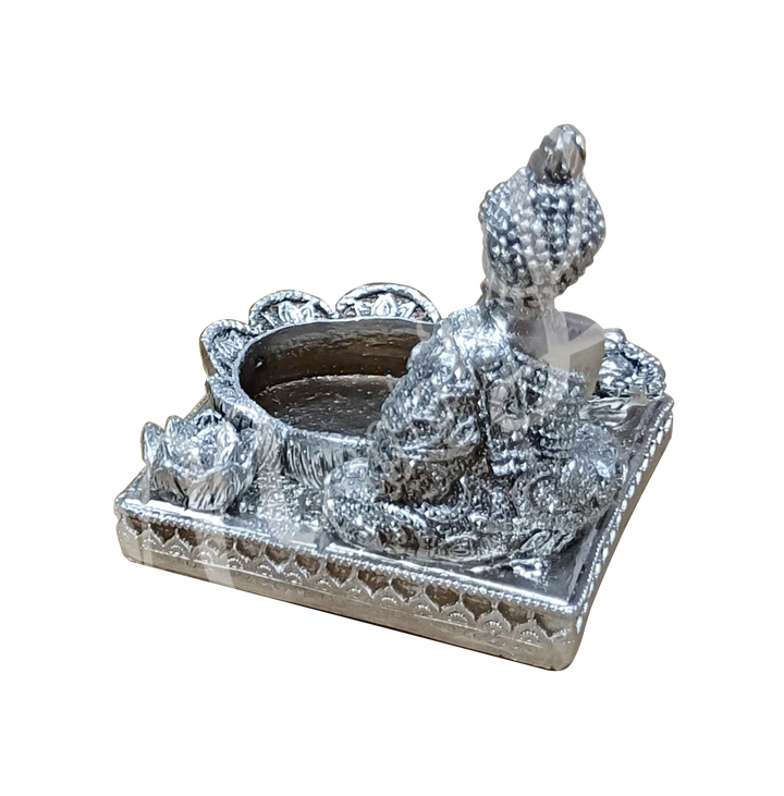 A silver-colored tealight and incense holder made of resin, featuring a Buddha with tealight and incense spaces at the front, shown from the back.
